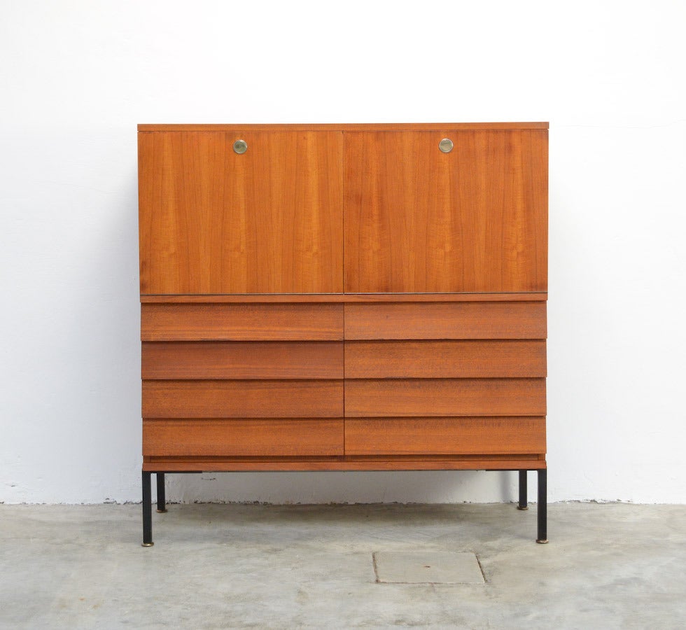 This minimal double writing cabinet is a design of the 1960s.
It is a high quality piece of furniture made of teak with nice copper details as the adjustable feet and the round handles.
The 8 drawers are pure and minimal. The doors are finished