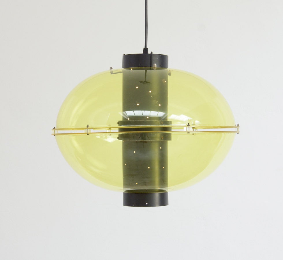 This ellipsoidal plexiglass hanging lamp Orbiter was produced by Raak, Amsterdam in the 1956.
The yellow-green plexiglass shells are fixed around a perforated black lacquered metal cylinder. This combination creates a special light effect.
This