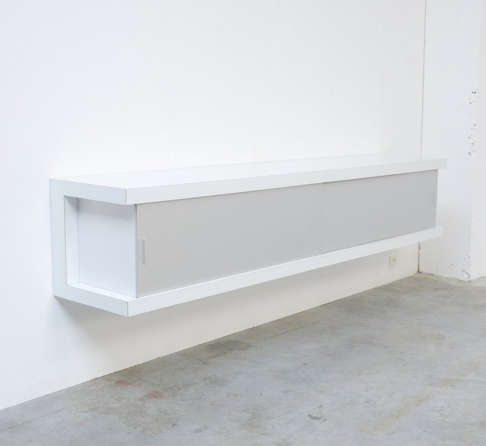 This minimal sideboard is a design of Horst Bruning for Behr. It is a great design of the 1960s.
The body is made of high quality white formica. The two sliding doors are made of brushed aluminium. Behind the left sliding door are three