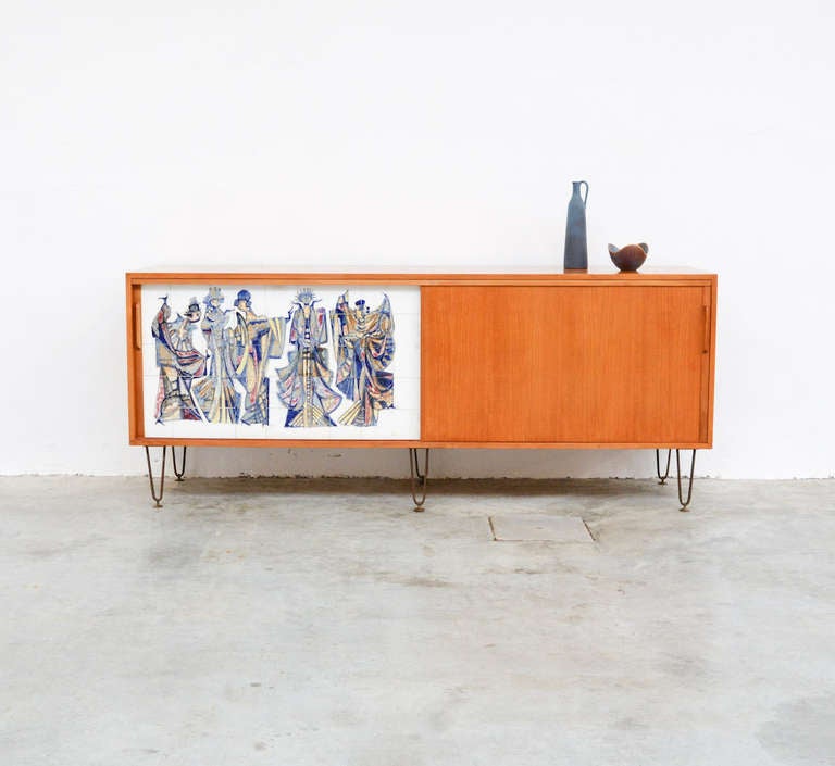 This magnificent tile sideboard is designed by Alfred Hendrickx for Belform in the 1950s.
It is a rare piece of furniture in light wood with a unique tile mosaic representing 5 dancing women in bright colours, signed Am 58.
This high quality