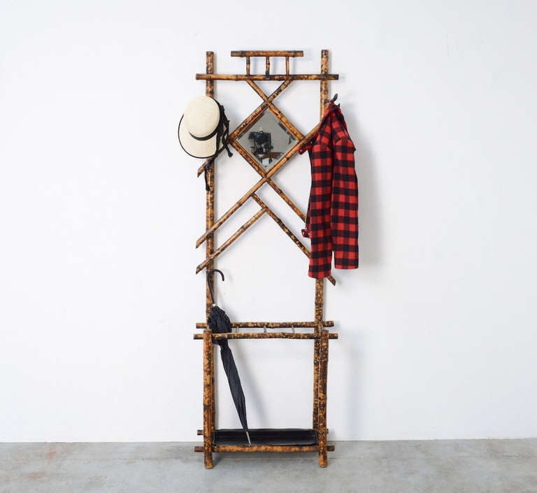 This real bamboo hall stand is really old and complete with an old small mirror and 5 cast iron hooks. There is also an umbrella stand with a metal tray.
This coat rack or hall stand has to be fixed against the wall.
It is a nice piece with a