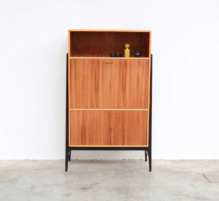 This bar cabinet was designed by Alfred Hendrickx for Belform in 1958.
The nice wood pattern, the details in light wood, the elegant black lacquered feet and the fine copper handles make it an elegant piece of furniture. This cabinet has 2 inside