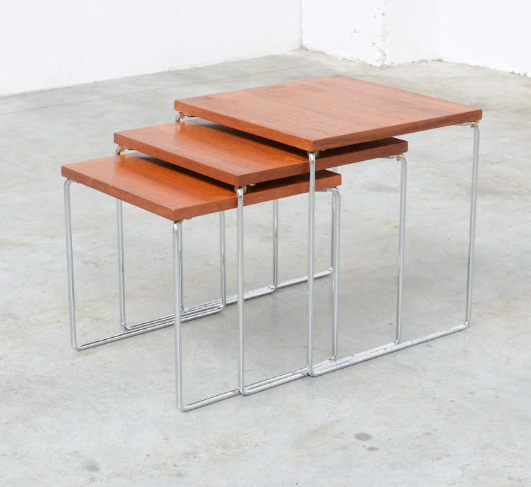 This nice set of tjree little cube nesting tables is a typical design of the 1960s. The top is made of teak and the base in chromium-plated metal. It is a light and practical set in very good vintage condition.<br />
<br />
Height: 34 34 31 cm