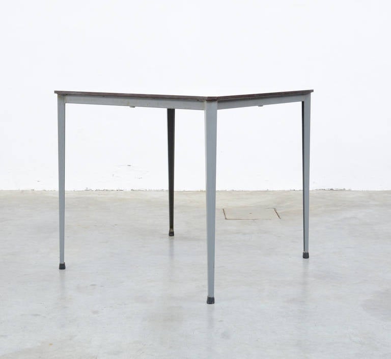 This minimal square table Recent is designed by Wim Rietveld for Ahrend De Circel in the 1970s.
The square top with cut-off angles is made of very strong white formica. The grey metal base has the typical folded legs.
This table is in perfect