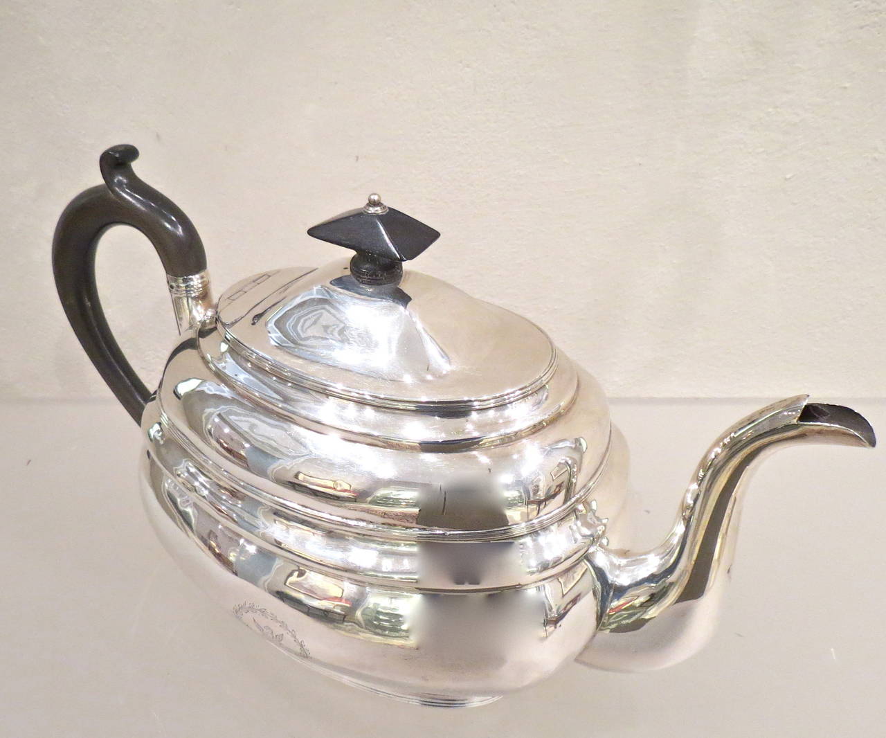 An antique silver teapot manufactured in Dublin in 1805 by Robert Breading. Harmoniously shaped, with a winged horse crest engraved on the lower section. Handle and top are made in ebony wood.