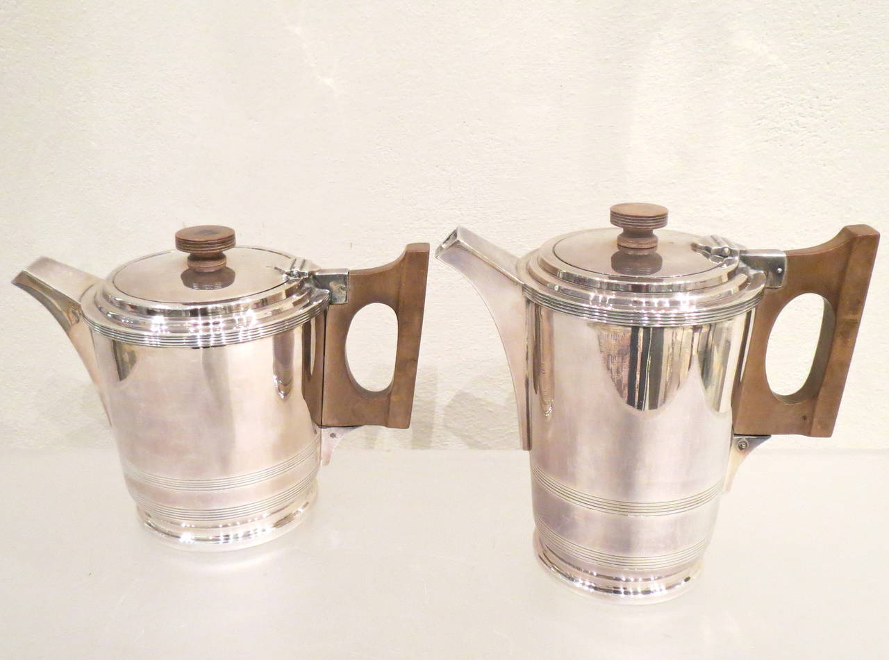 Four-piece silver plate tea and coffee service, stepped Art Deco bases and lids, with wood handles, comprising a coffee pot, tea pot, sugar and creamer by Walker and Hall Sheffield. Measurements: Coffeepot height cm 17.5, width cm19, depth cm 10.5.