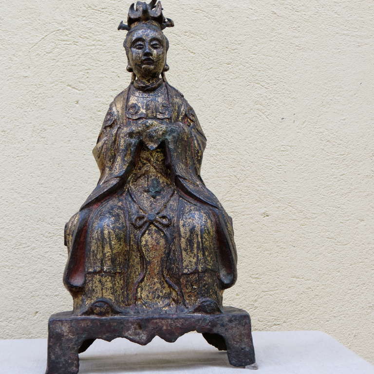 La reine mère de l'Ouest est représentée en position assise, les mains devant sa poitrine, tenant un 