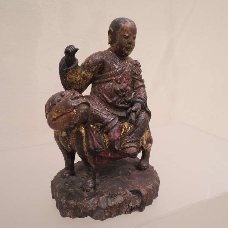 
A Fine hand-carved and Lacquered wood figure of a Luohan Arhat, Buddha' disciple. 
Seated in royal ease on a standing lion, wearing long flowing robes.
China, Kangxi Kingdom 1661-1722.
The carved and painted seated holy man with shaved head perched