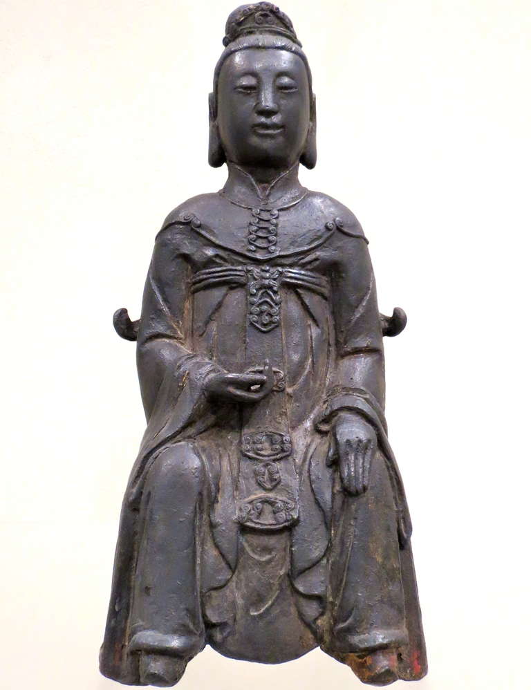 A cast bronze figure of a Taoist Ancestor, dressed in decorated long-sleeved robes, sitting on a throne in a regal position.