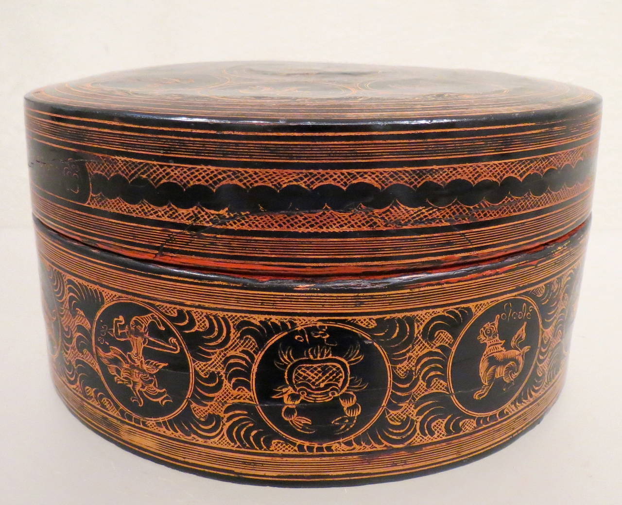 Cylindrical red lacquer betel-box, 'kun it,' with internal tray. This betel-box is made up of the following elements: A finely decorated lid; an internal tray with a heavy lip and red lacquer inside and orange/brown outside, Burma, late 19th century.