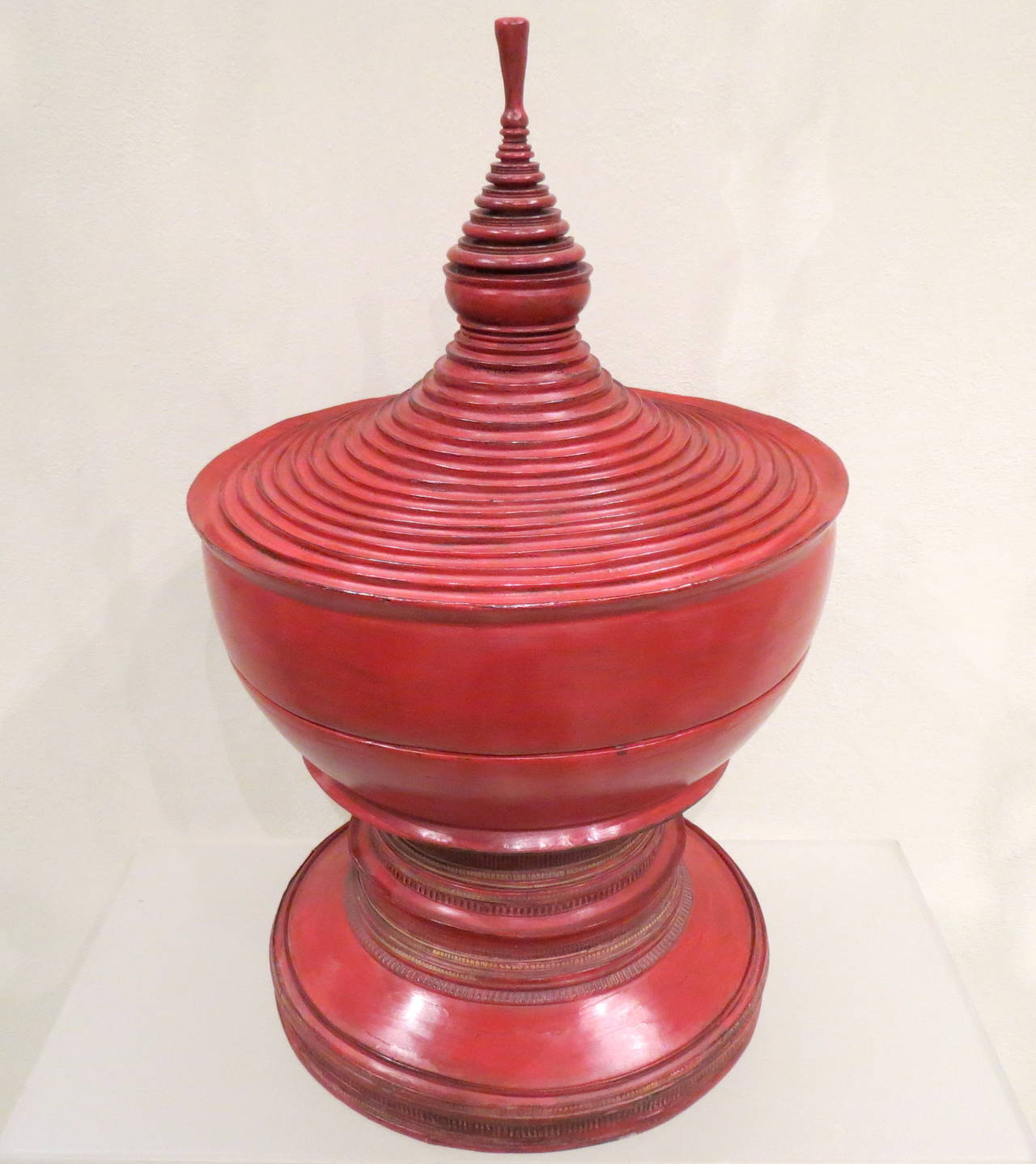 Late 19th century Burmese red lacquer special ceremonial offering vessel.
Detailed spire form the top of
the lid, stepped curved ring
molded bowl above round
base. Multiple layers of red
lacquer adorn this
pagoda shaped ceremonial
vessel.