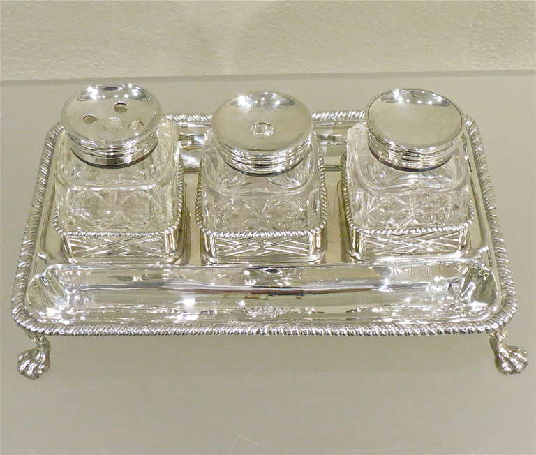 A fine and impressive antique George II crested sterling silver double partners inkstand with three silver mounted finely cut-glass inkwells. The body of the inkstand is ornamented with a gadroon decorated border to the rim. The square cut-glass