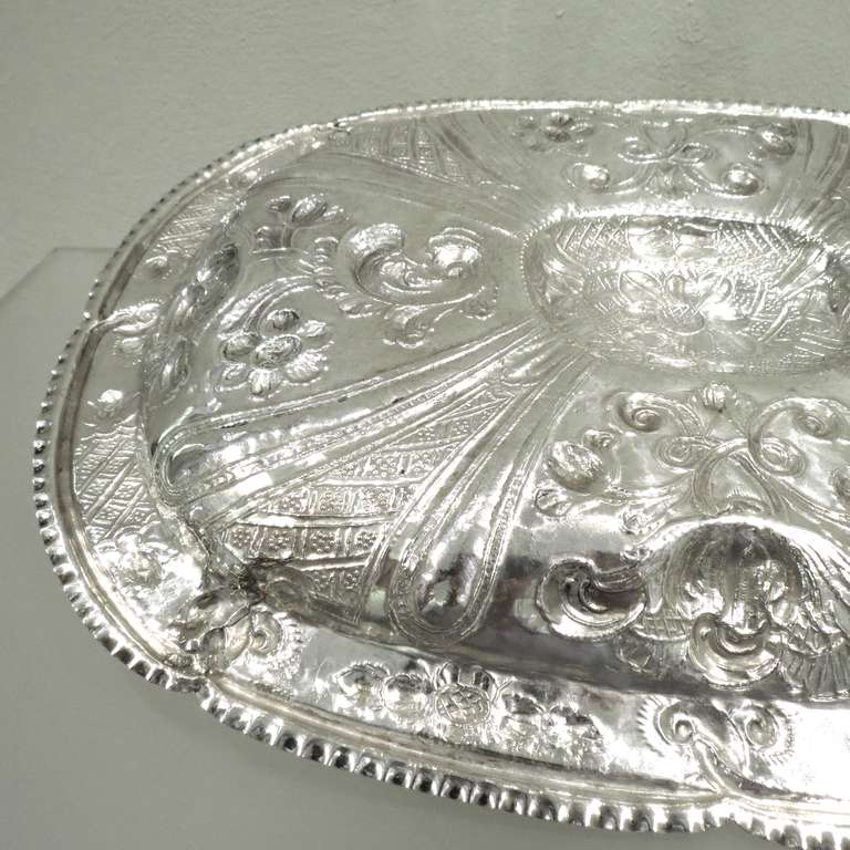 Antigua bandeja ovalada de plata colonial española del siglo XVIII, decorada con motivos florales repujados y cincelados, estampada en la parte posterior con la marca del fabricante: Francisco Sánchez Taramas, Granada 1770. Medidas: Profundidad 29
