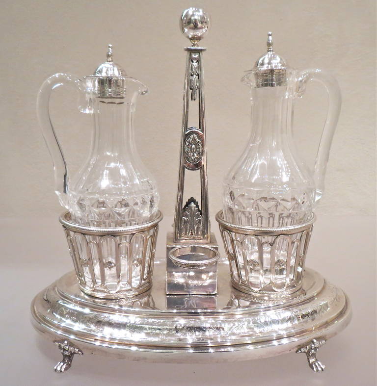Eleganter und außergewöhnlicher antiker französischer Öl- und Essigkrugständer aus Silber und Kristall. Der Griff in der Mitte hat die Form eines Obelisken. Die Tassen stehen auf einem ovalen, fein gravierten Sockel, der auf vier Löwentatzen ruht,