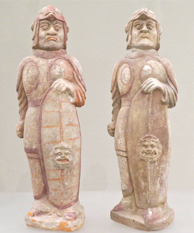 A wonderful and rare pair of ancient Chinese Northern Ch'i dynasty (550-577 AD.) Polychrome terracotta figures. The warriors shown standing tall, they both wear close fitting helmets and clutch oblong shields. Their faces are individually molded and