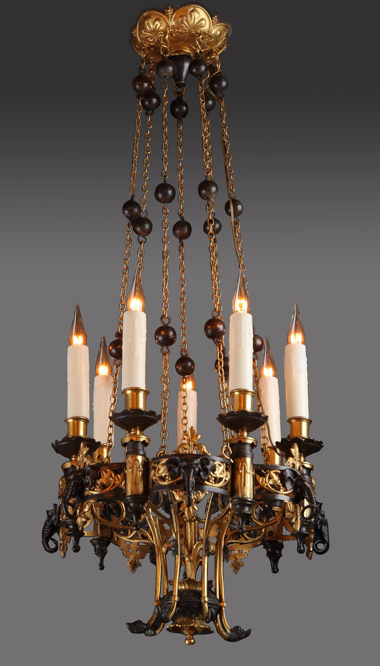 Rare pair of oriental chandeliers, made in two patina bronze. Seven-light arms are distributed around a lobed pierced gilt bronze wreath, decorated with stylized foliage and elephant heads cast in relief, supported by seven gilded chains embellished