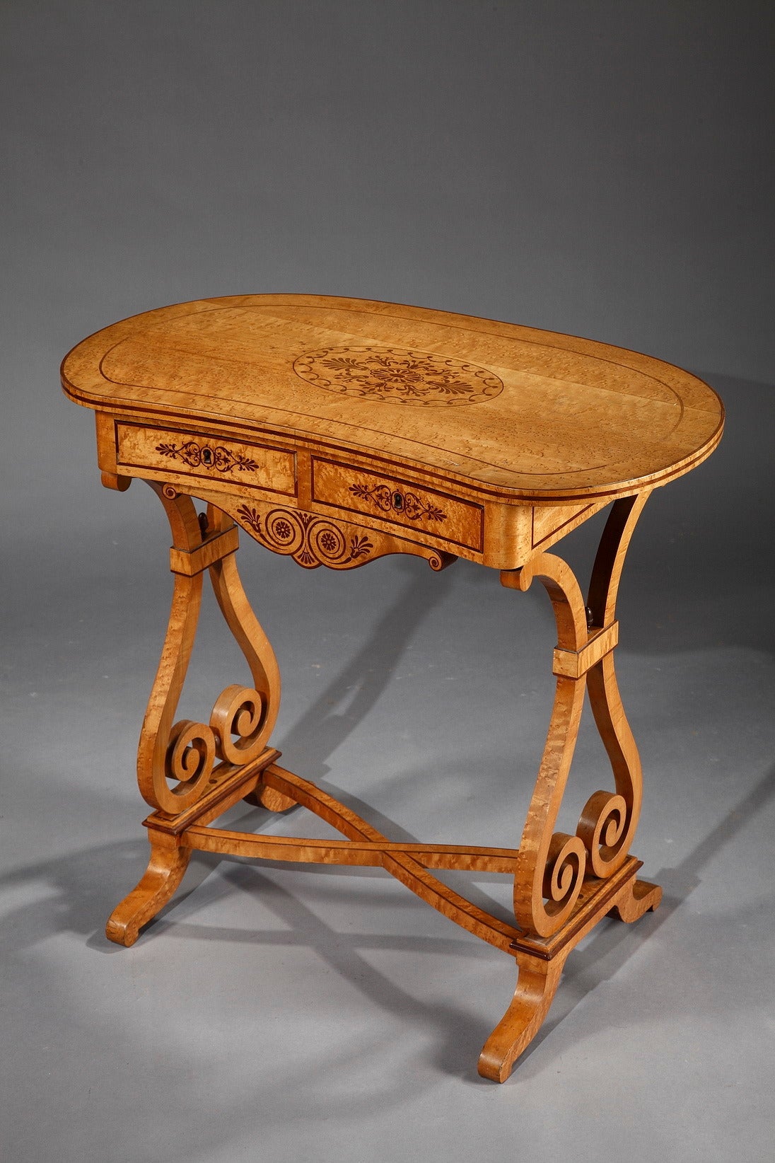 A very fine Charles X writing table veneered with lemonwood and amaranth. The kidney-shaped top is veneered with lines of amaranth and a central medallion with stylized palm leaves. The belt presents a frieze of amaranth marquetry. This table opens