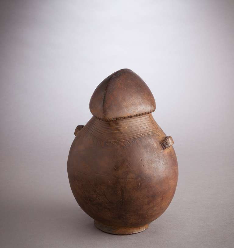 The Shi peoples are agriculturalists living on the shores of Lake Kivu in D.R. Congo. Artistically they are best known for their distinctively carved cups and pitchers. This example features a smoothly formed lid which, like the neck and lugs of the