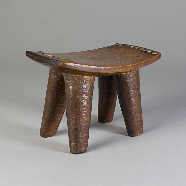 A sense of mass and monumentality inheres in this four-legged stool despite its relatively small size. Simplicity and grandeur are simultaneously expressed in this utilitarian form, which is finished with a deeply aged patina and rows of applied