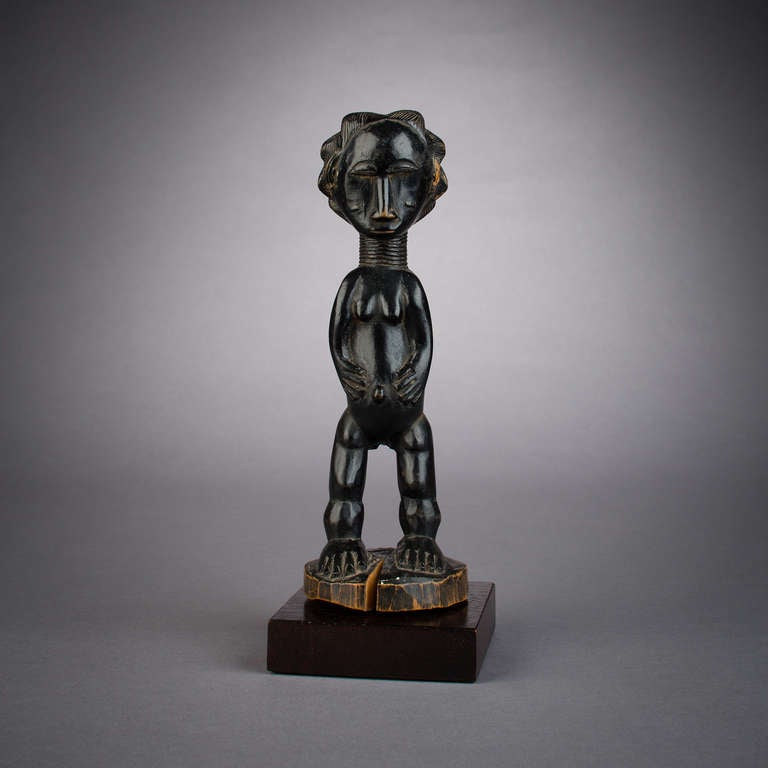 A beautiful and lustrous black patina adorns this gorgeously carved Akye figure, handsomely proportioned with its sinuous contours. Each portion of this figure has seen its share of care on the part of the carver, from its intricately detailed