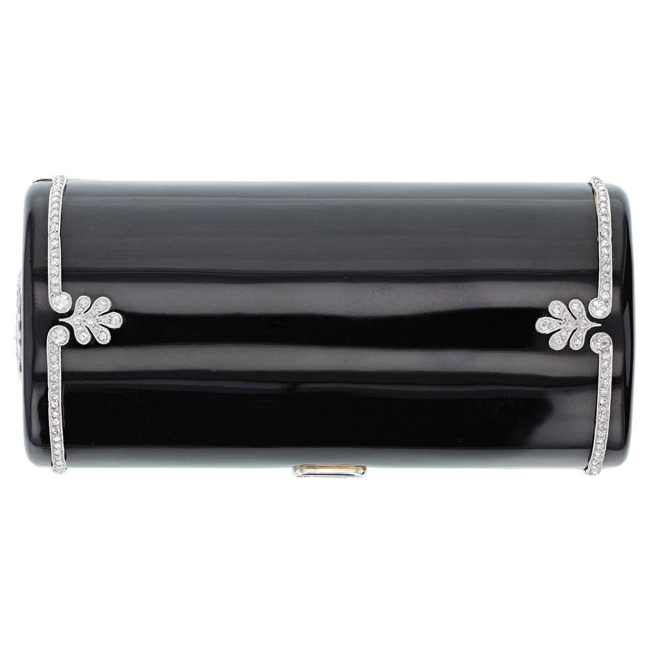 The black enamelled 18 carat yellow gold cylindrical case applied at each side with a line of millegrain-set rose-cut diamonds and similarly set palmette motifs, a rose diamond-set circle to one end, diamond set thumb piece, fitted with a cigarette