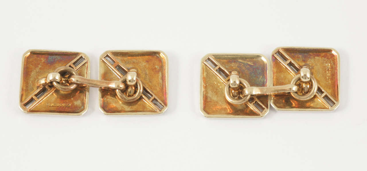 A fine pair of 14 karat yellow gold double sided cufflinks, faced in platinum, with a diagonal line of five channel set, baguette cut diamonds, bordered with black enamel lines. Square in shape with rounded corners.
Measures 13mm across.
1930’s