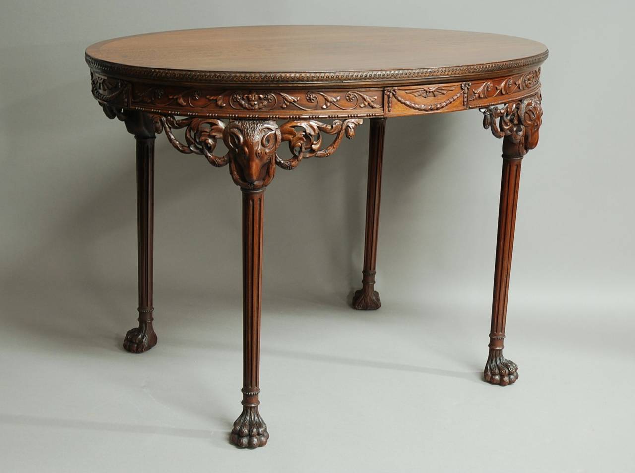 A superb quality early 20th century mahogany centre table in the manner of Robert Adam.

This table consists of a super quality, figured and crossbanded mahogany top with a sophisticated carved edge.

The recessed frieze consists of carved
