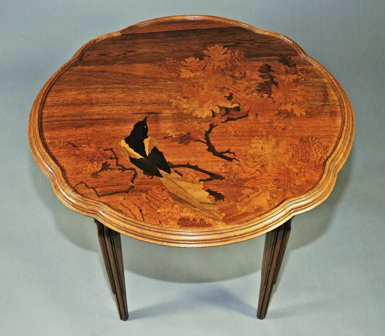 An early 20th c signed occasional table by Emile Galle.

The frame is made of beech and the top is veneered & inlaid with Hungarian ash & other exotic woods depicting a bird, possibly a magpie, within foliage.

The signature is found within the