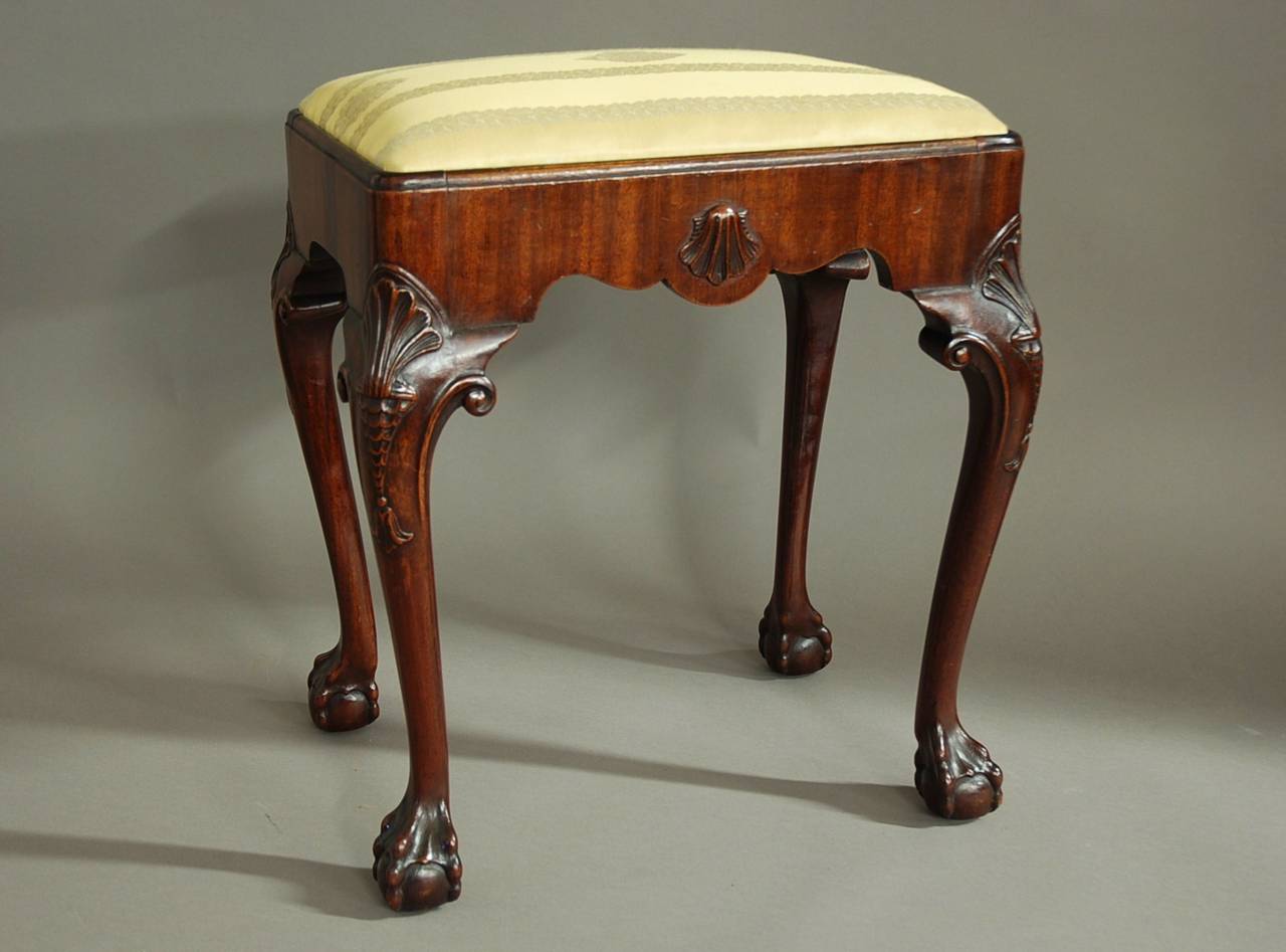 An early 20th century walnut cabriole leg stool with a drop in seat.

This stool consists of a quadrant retaining moulding at the top with shaped seat rails veneered with straight grain walnut onto walnut.

The drop in seat is covered in a pale