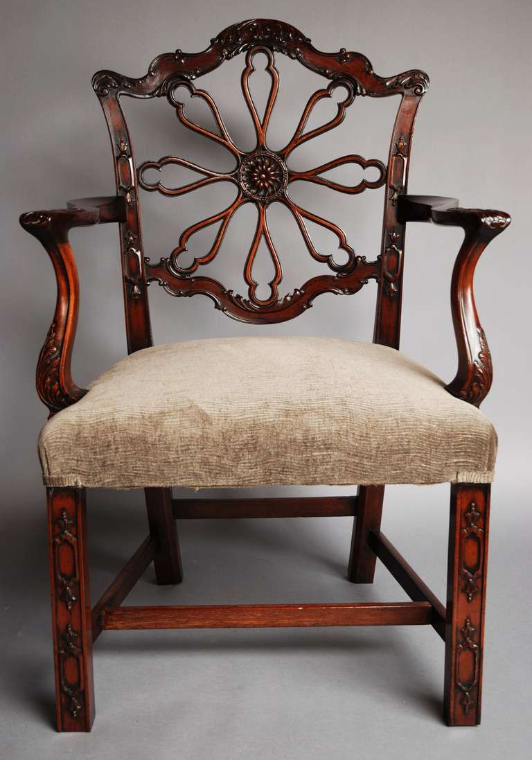 A late 19th-early 20th century mahogany open armchair in the Chippendale style. 

The back has pierced radiating wheel splats with a carved central patera. 

The top, side and bottom back rails are all profusely carved with acanthus decoration.