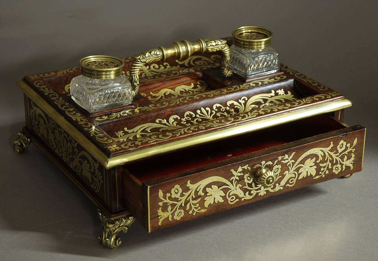 A superb Regency rosewood and inlaid brass desk Stand / inkstand in excellent original condition.

This piece consists of a rosewood desk Stand intricately inlaid with brass 'boulle' decoration to the top and also to all sides.

The brass handle