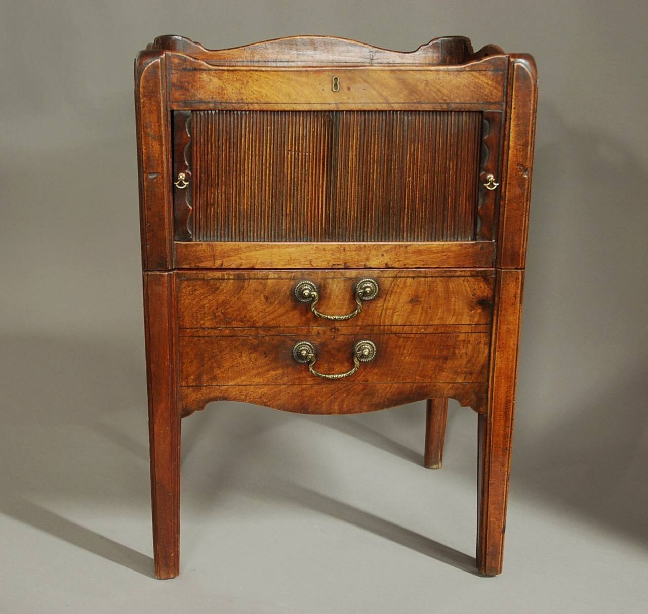 A late 18th century mahogany night table of superb patina.

This piece consists of a shaped and pierced gallery to the top supporting a finely figured solid mahogany top of superb patina (color).

The top front rail has an escutcheon but this is