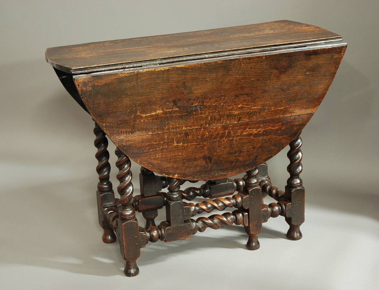 An unusual late 17th century oak gateleg table of small proportions and good patina (color).

This table consists of an oval plank top of good color with a drawer at one end and is supported by unusual barley twist turned legs and
