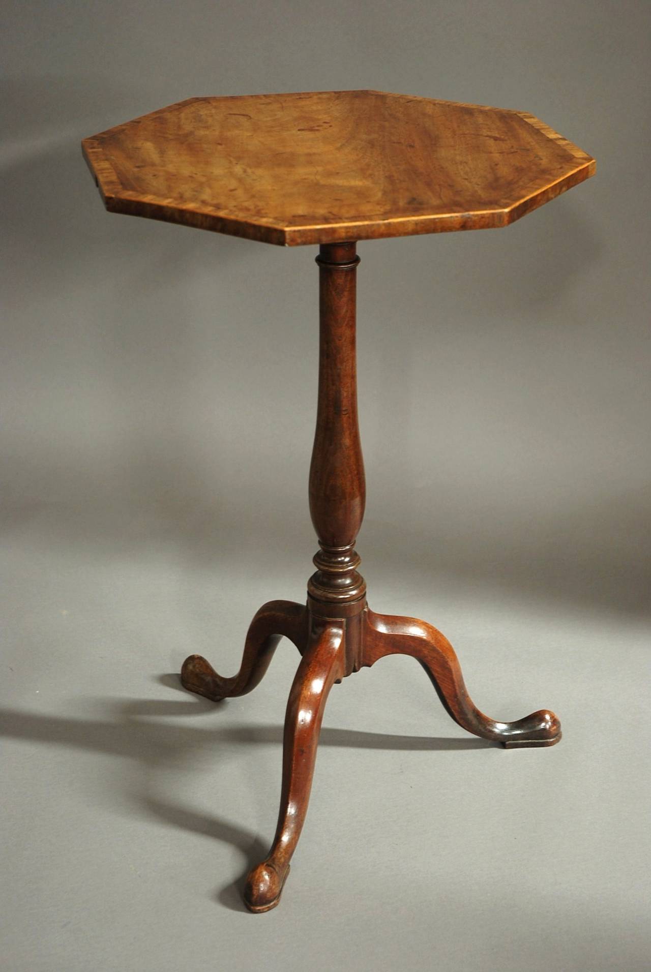 A George III octagonal mahogany tilt-top table with tri-form base of superb patina and good proportions.

This table consists of an octagonal mahogany top of superb color with a banding of mahogany and box wood stringing with a cross banded