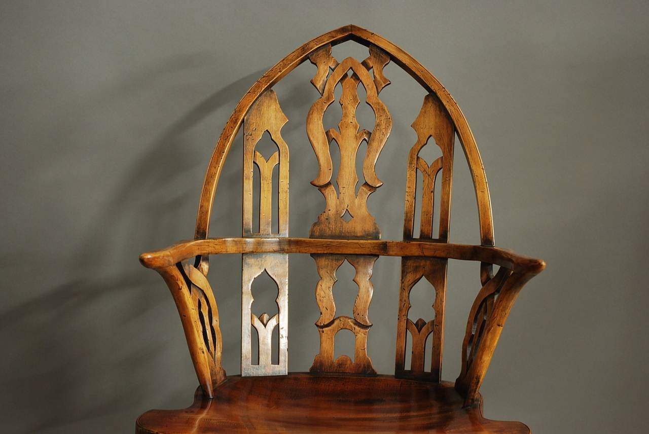 A pair of late 20th century Gothic style cherry Windsor armchairs of large proportions.

These chairs consist of a typical Gothic style arched back with piercing leading down to inswept arm supports.

The elm seats are shaped and lead down to