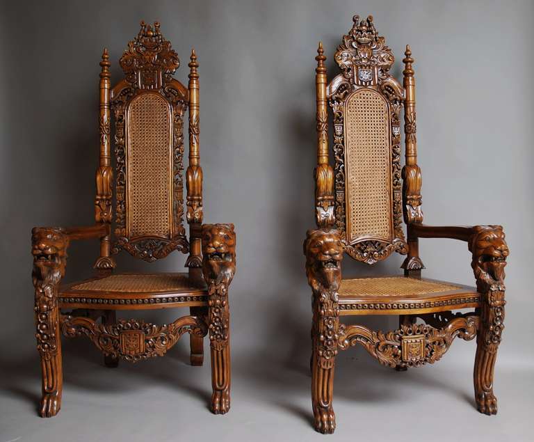 A large pair of highly decorative hardwood Ceremonial chairs with cane backs and seats in the Continental style.

The backs consist of a double cane central section with carved armorial & foliage decoration to the side and to the top.

The back