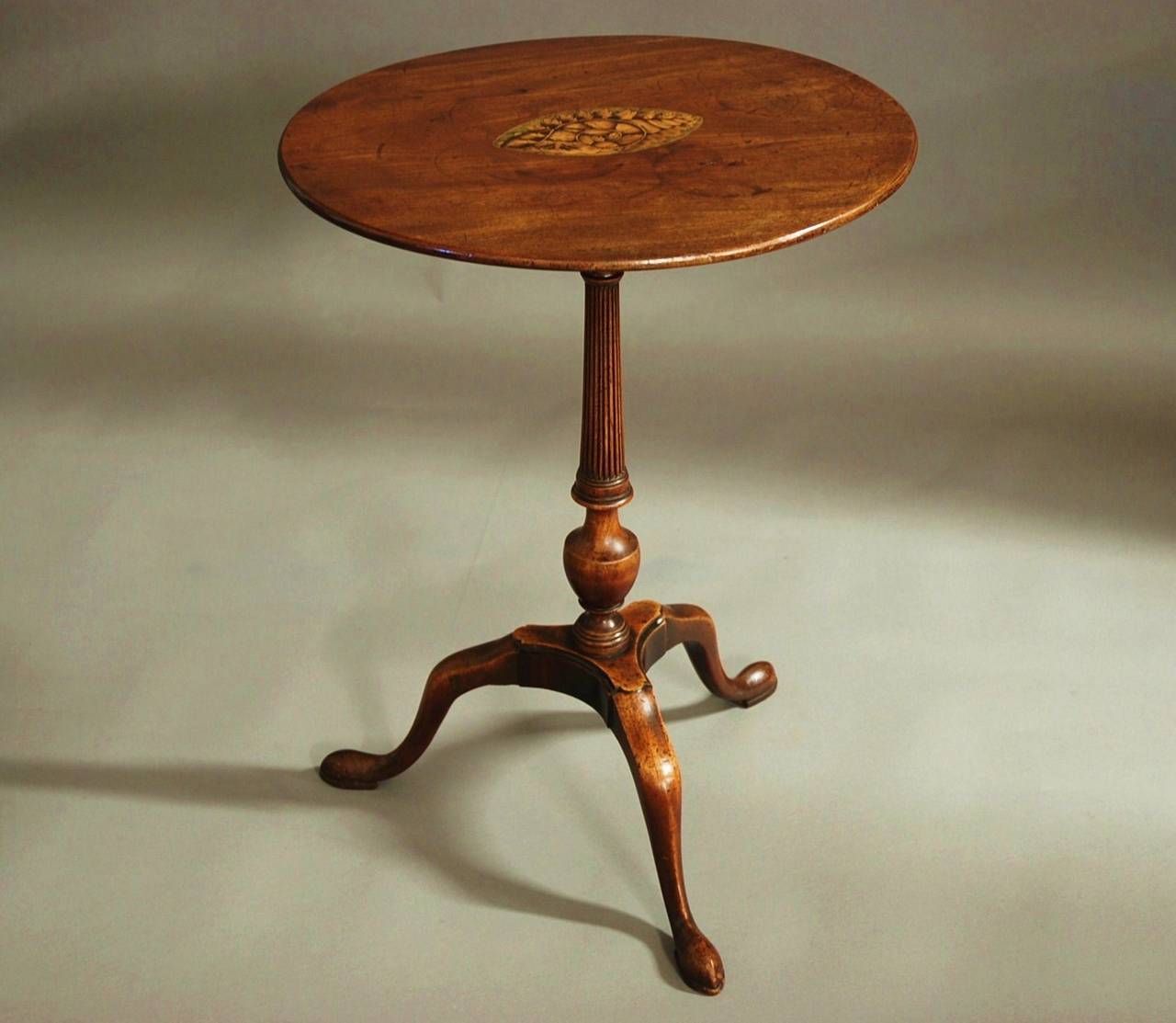 An 18th century tripod occasional table/wine table of oval form of good patina (color).

This table consists of a finely figured solid mahogany oval top with oval inlaid shell and leaf decoration in boxwood and stained sycamore.

This leads down