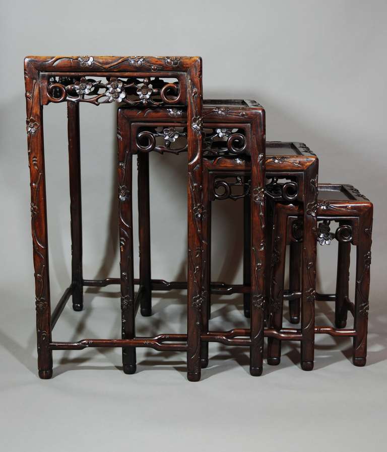 A late 19th century set of four graduated Quartetto nest of Chinese hardwood tables. These tables are in good condition and have a good patina (color). Each table has carved floral and foliage decoration around the top and this is also carried on