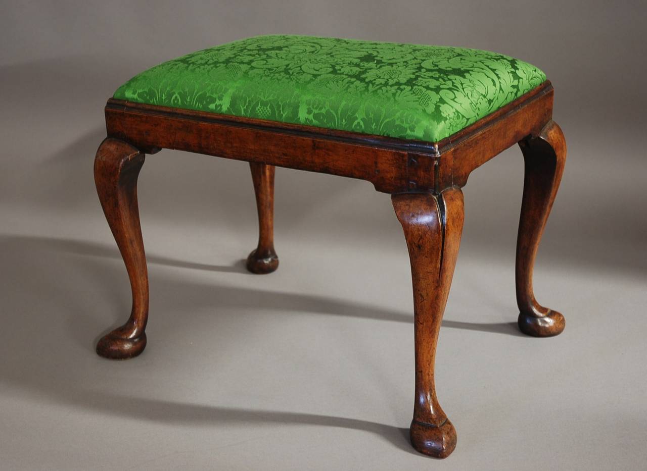 An early 20th century walnut cabriole leg stool in the Queen Anne style.

This stool consists of a drop in seat covered in a green  jacquard silk fabric made in Sudbury, Suffolk, UK (this could however be easily re-upholstered by the purchaser to