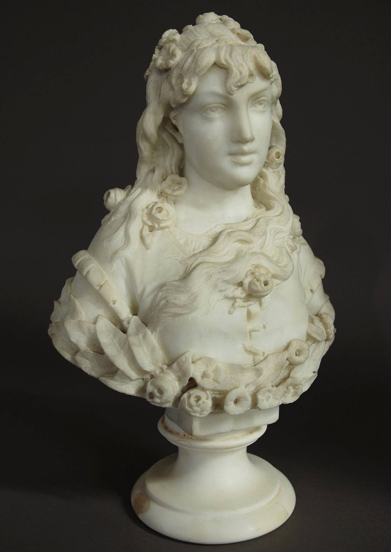 A late 19th century finely carved marble bust of a young lady, carved from white carrara marble, possibly Italian.

This piece is nicely carved sculpture of a fresh faced young lady with long hair with roses both in her hair and clothing.

The