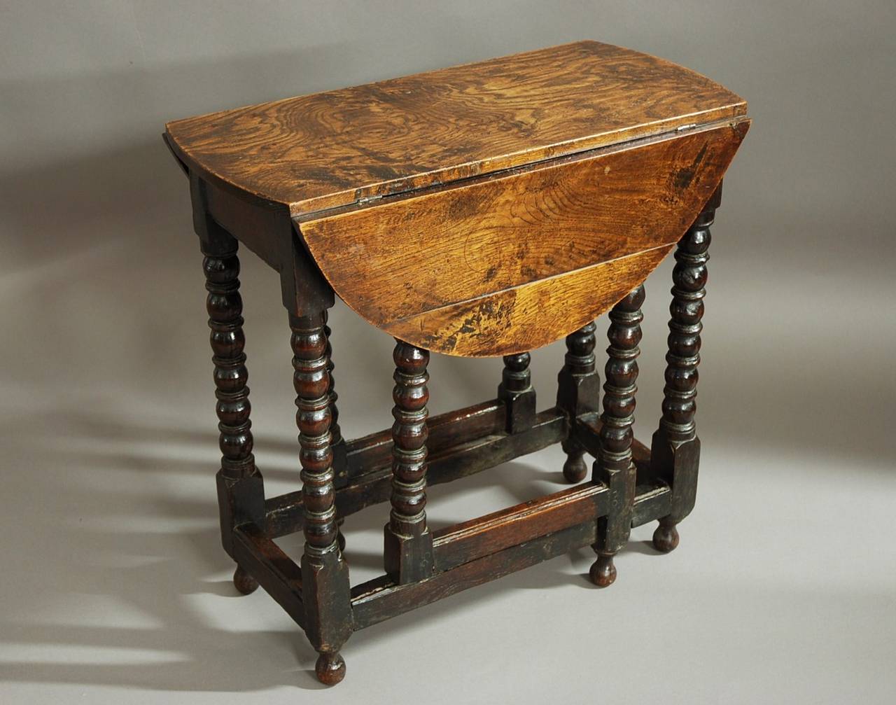 An extremely rare late 17th century oak and elm gateleg table of small proportions and superb patina from the William & Mary period.

This table consists of a well figured elm top of superb patina (color) leading down to an oak base with bobbin
