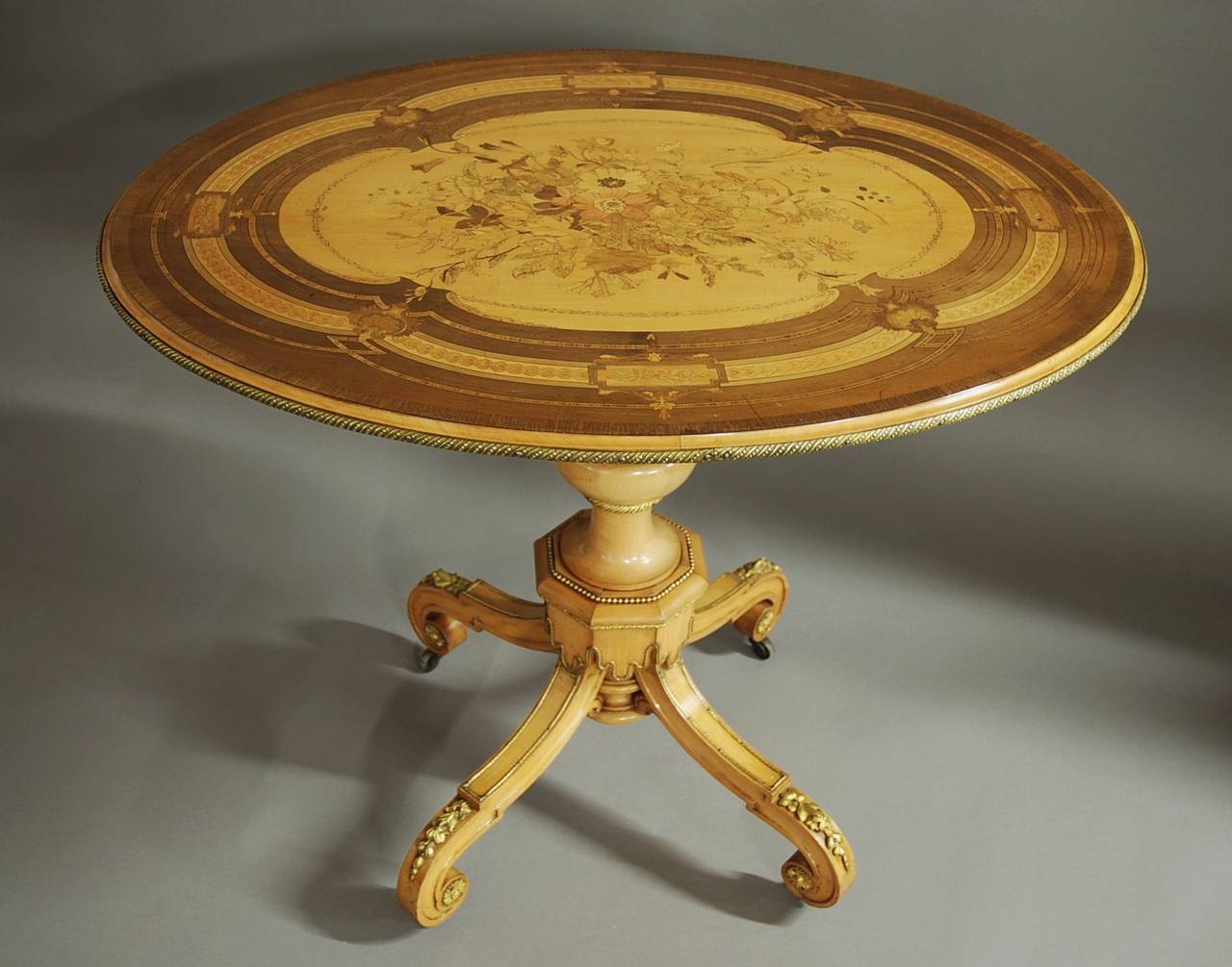 A mid-19th century exhibition quality sycamore inlaid centre table of elliptical form in the manner of Jackson & Graham (1836-1885).

The elliiptical shaped top consists of a finely executed marquetry flower and foliage design of superb quality