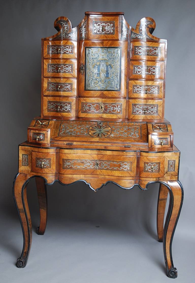 A rare South German 18th century walnut bureau cabinet on stand of exceptional quality with pewter inlaid decoration.

This wonderful item consists of three sections starting with a scroll shaped top with a small central drawer inlaid with pewter