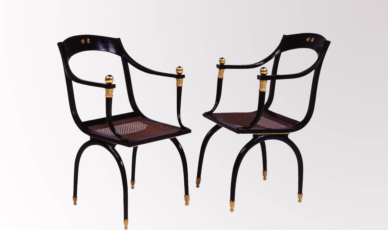 19th century inspired chairs. The curved back with Emilio Terry’s gilt bronze initials, continuing to the armrests supported by horn of plenty with a gilt sphere above. The arched legs ending in gilt bronze foliage ornaments. Caned seats. Lacquer