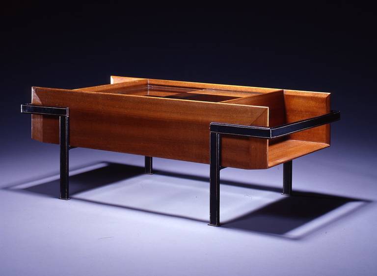 Table designed in 1960, this design did not enter in production.
Rectangular teak case with sliding glass panels over glass-bottomed compartment, on black leather covered flat steel frame.