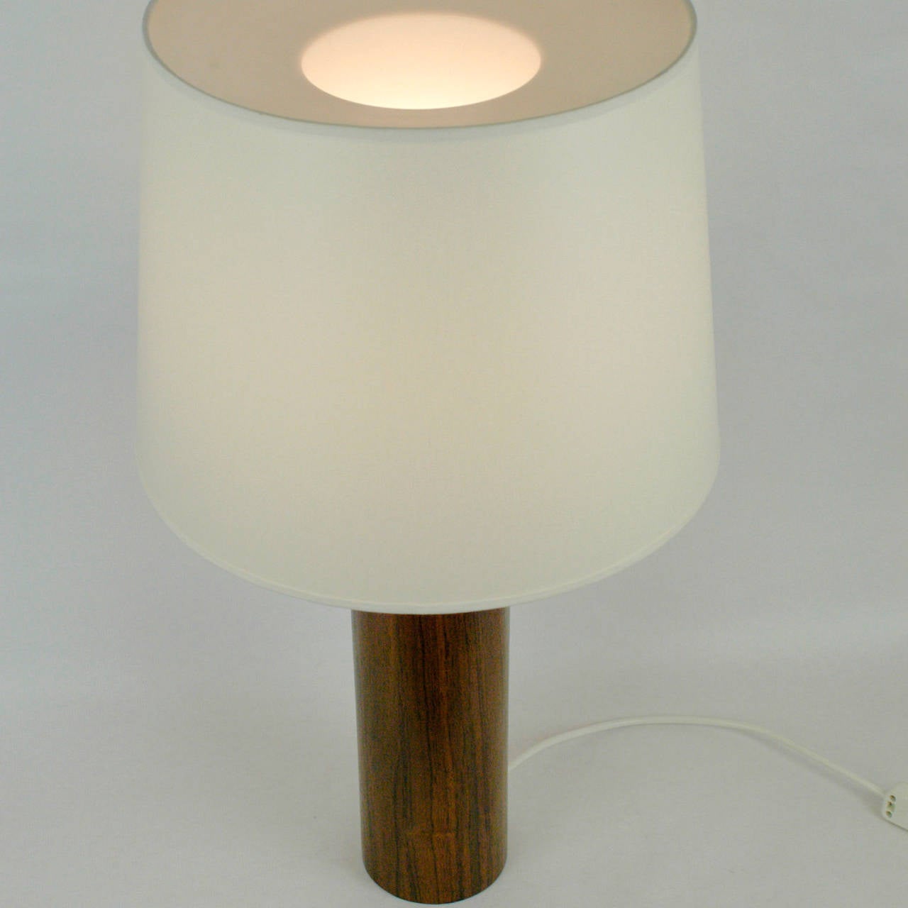 Timeless pure classic Scandinavian Modern table lamp designed by Uno & Östen Kristiansson for Luxus Vittsjö Sweden. It has a cylindrical rosewood venered base and a renewed cream white shade, original manufacturers label still on the base
Perfect
