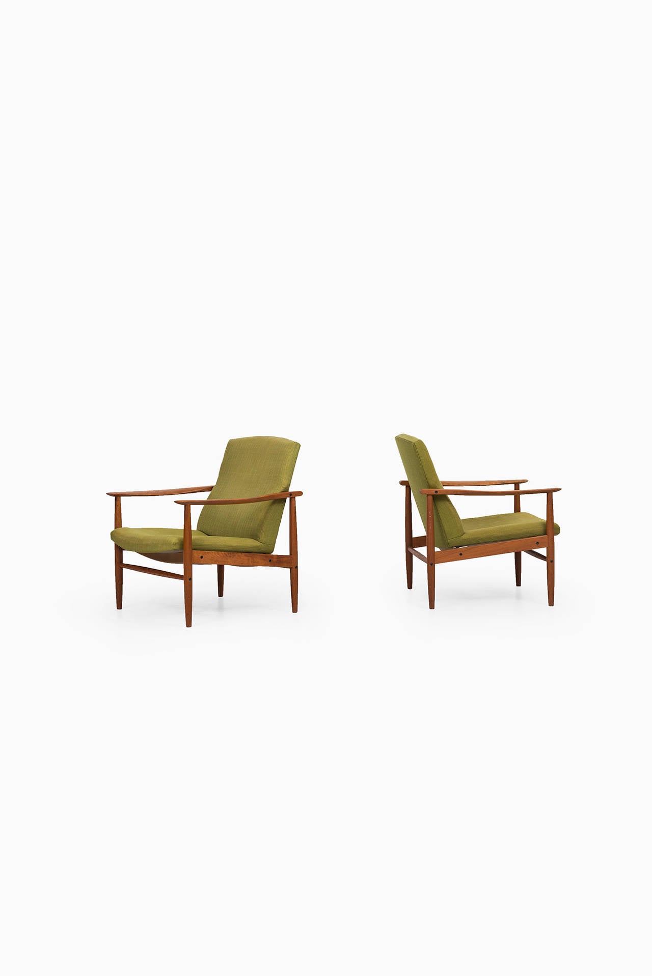 A pair of mid century easy chairs in teak and green fabric. Probably produced in Denmark. The padding is dry so we recommend to re-upholster.