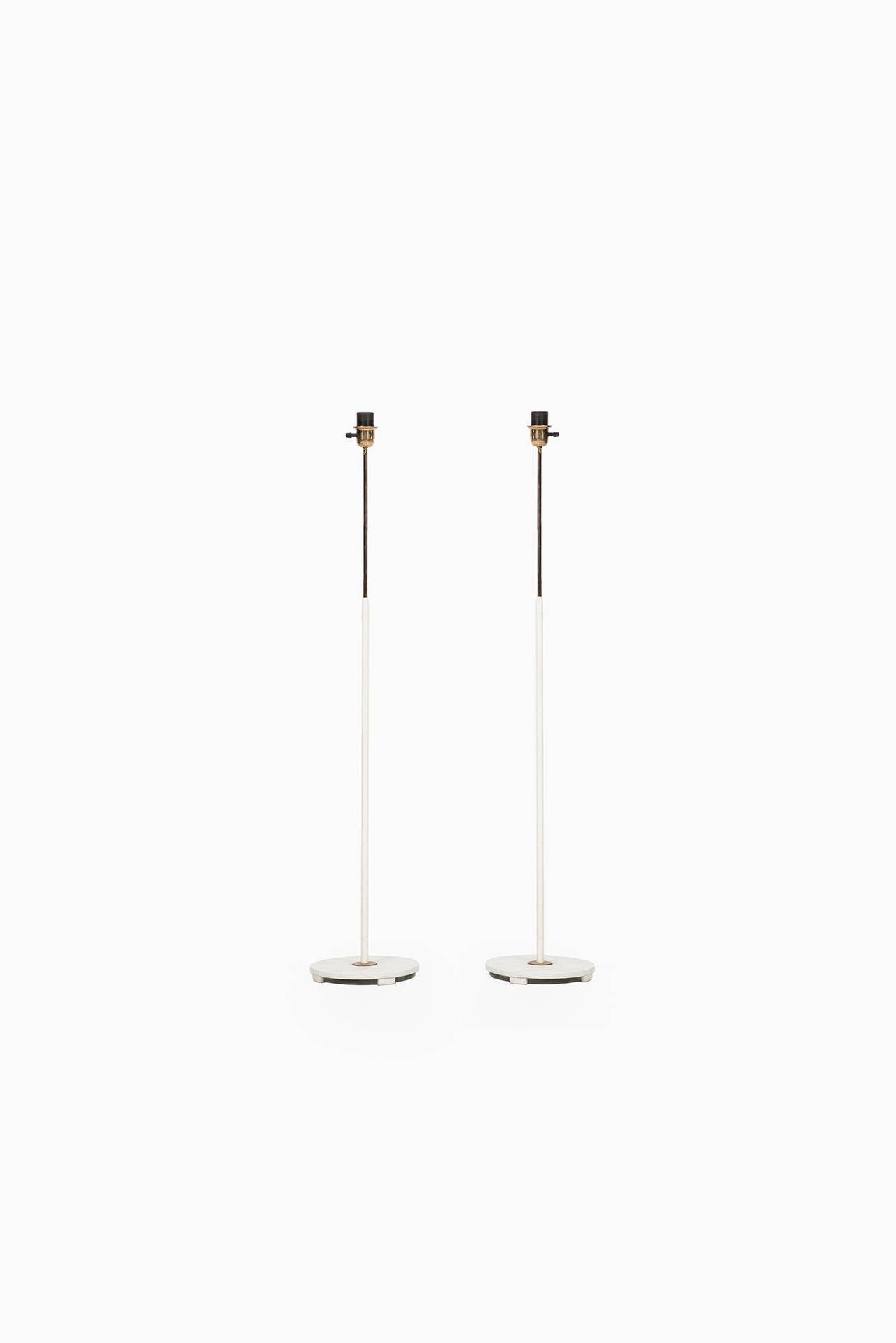 A pair of white lacquered floor lamps with brass details produced by ASEA in Sweden. Please note that these floor lamps are being sold without any lamp shades.
