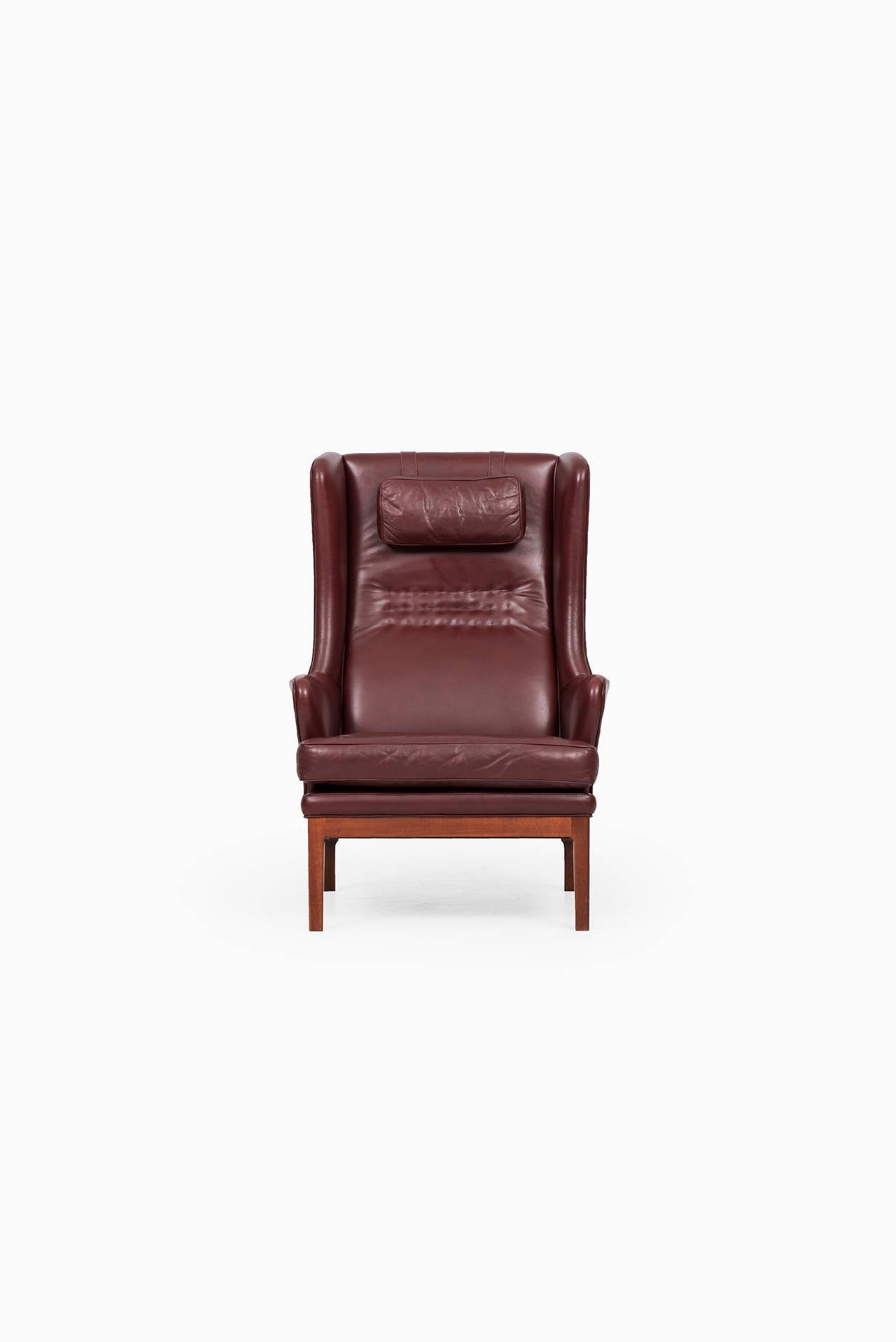 Rare wingback easy chair in dark stained beech and dark red leather designed by Arne Norell. Produced by Norell AB in Sweden.