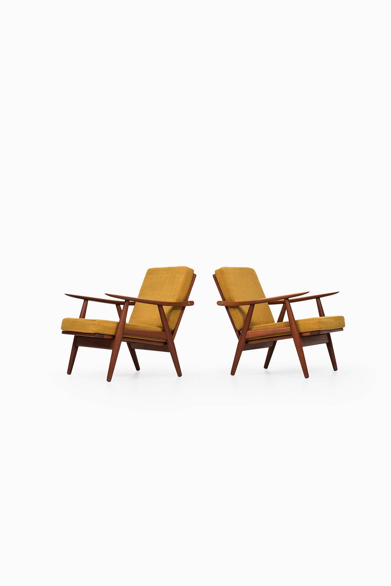 A pair of easy chairs model GE-270 designed by Hans Wegner. Produced by Getama in Denmark. Teak, brass and original yellow fabric.
